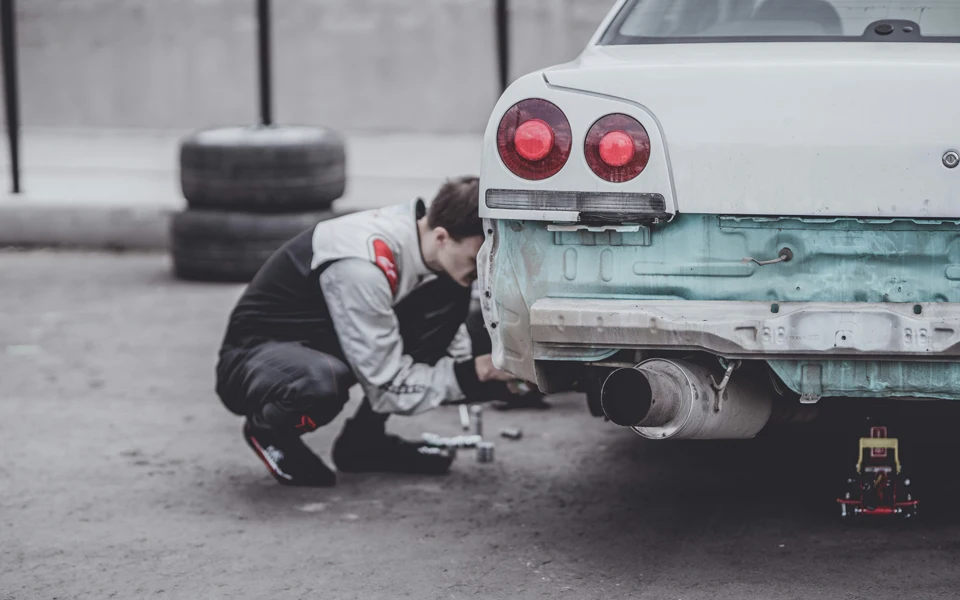 Man repairing an old car in a garage
