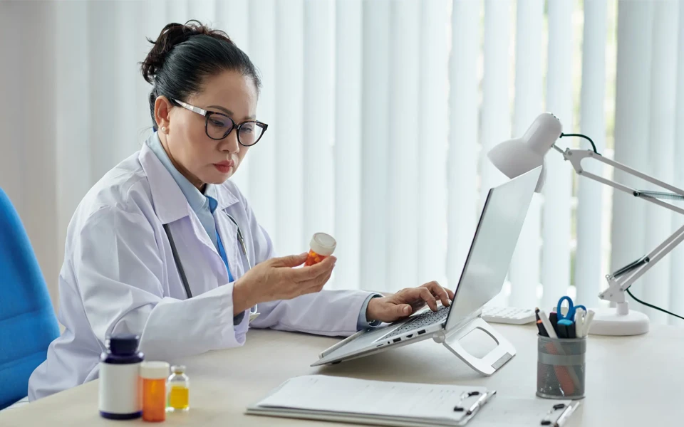 The image shows a doctor explaining how tele-health insurance works in Dubai.